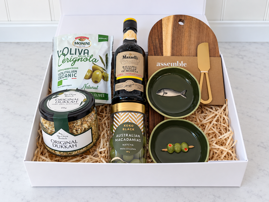 The Olive Grove Gift Box with olives, balsamic vinegar, dukkah, matcha white chocolate macadamias, two green ceramic dishes and an acacia board