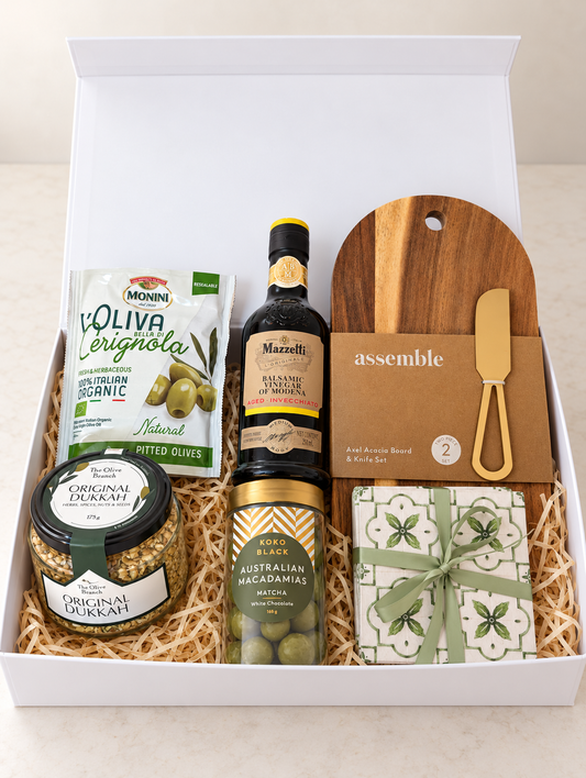 The Tuscan Table Gift Box with balsamic vinegar, olives, dukkah, matcha macadamias, acacia board and knife, and ceramic coasters.